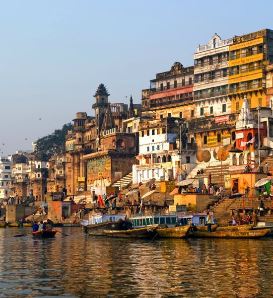 The ghats of Varanasi, India, at sunrise, seen from a boat on the Ganges River.