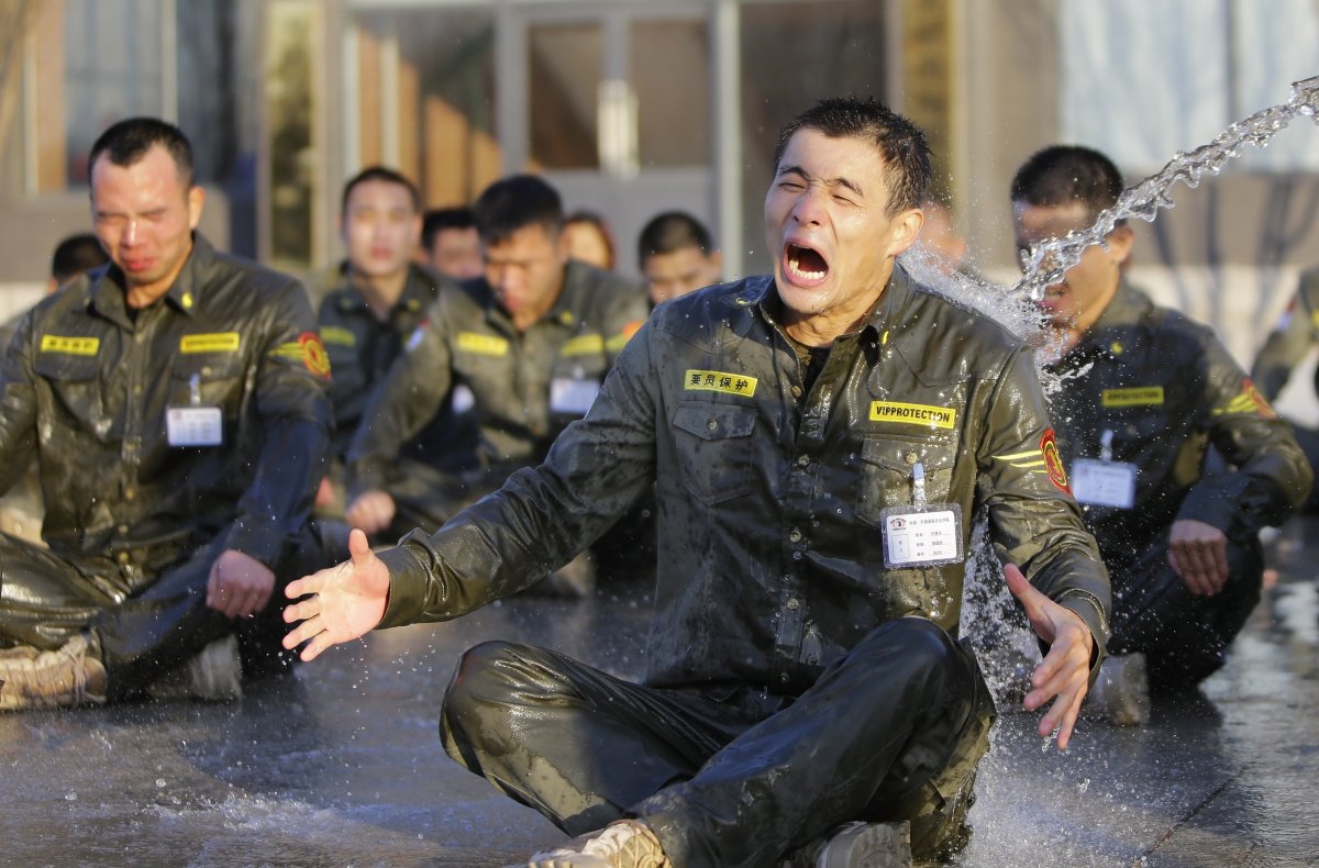A trainee reacts as he is drenched with water during Tianjiao Special Guard Security Consultant training.