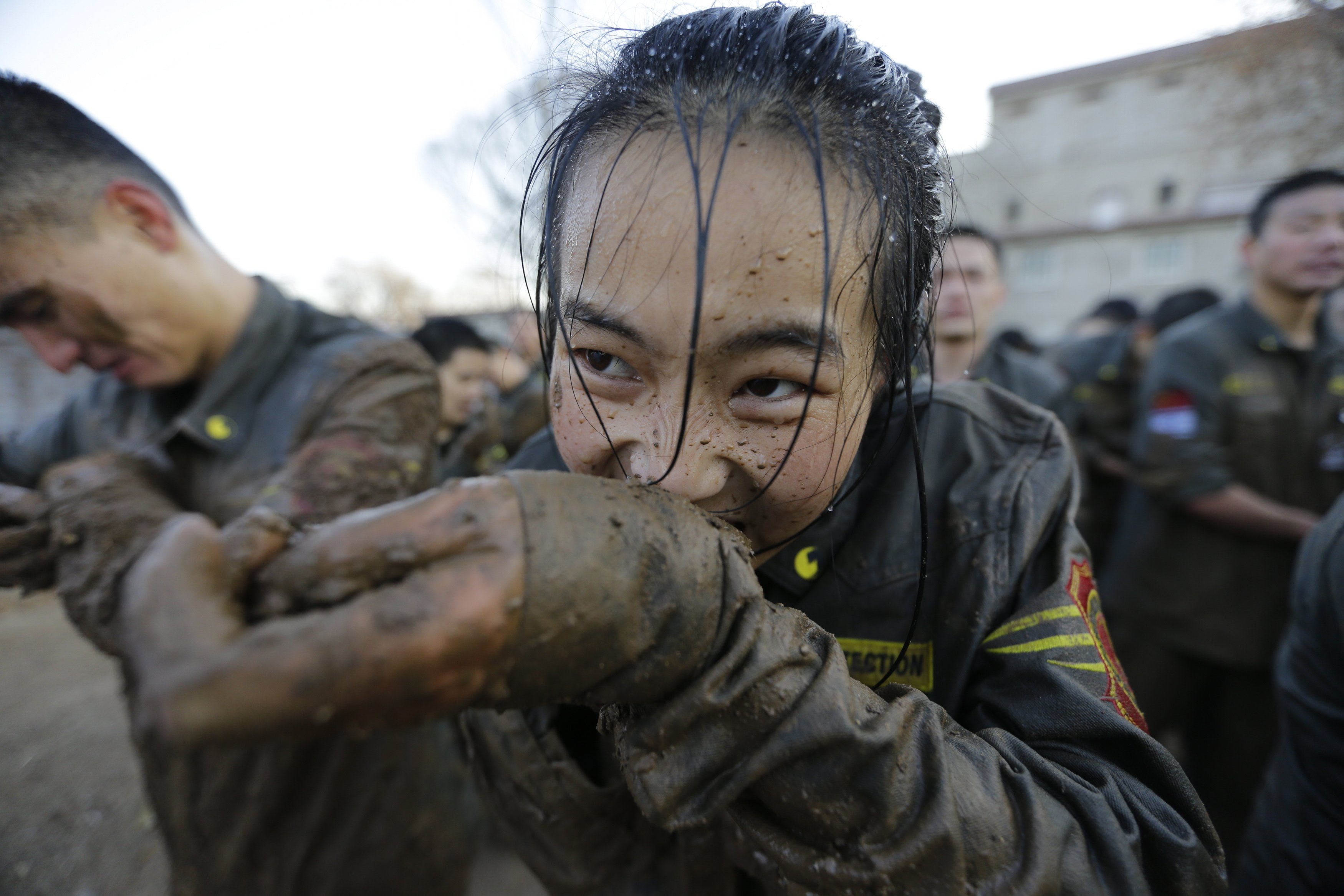 A female student opens her cufflinks with her teeth, after crawling through mud at Tianjiao Special Guard Security Consultant camp on the outskirts of Beijing.
