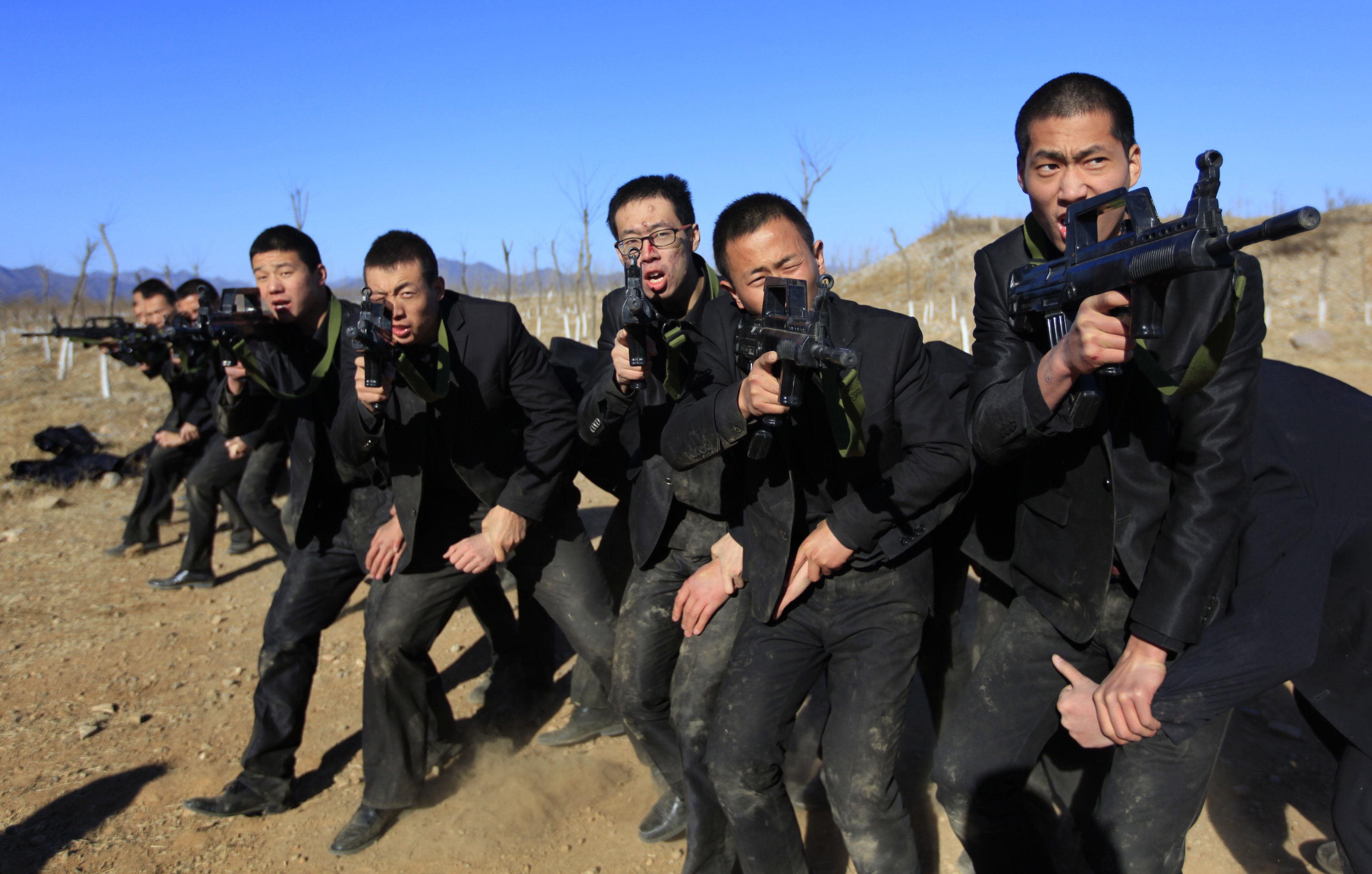 Students holding replica 95 semi-automatic rifles practice protecting their employers at a shooting training field managed by the military during Tianjiao Special Guard Security Consultant training on the outskirts of Beijing December 14, 2013.