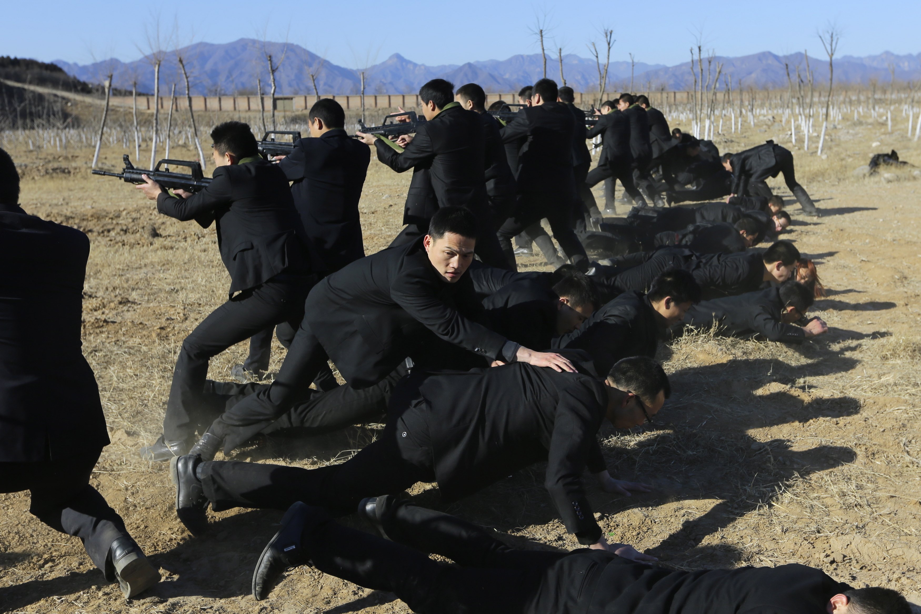 Students holding replica 95 semi-automatic rifles practice protecting their employers at a shooting training field managed by the military during Tianjiao Special Guard Security Consultant training on the outskirts of Beijing December 14, 2013.