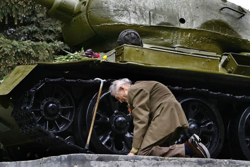 Russian war veteran kneels beside the tank he spent war in which was turned into a monument.