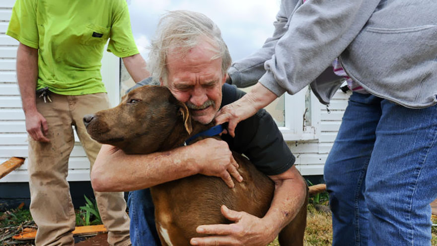 Greg Cook hugging his dog after her found her alive during a tornado that destroyed his home in March of 2012.