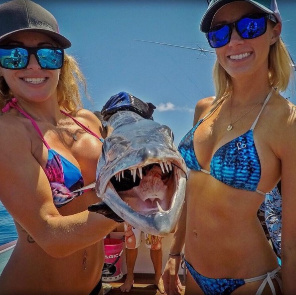 Funny picture of two bikini girls holding a smiling fish.