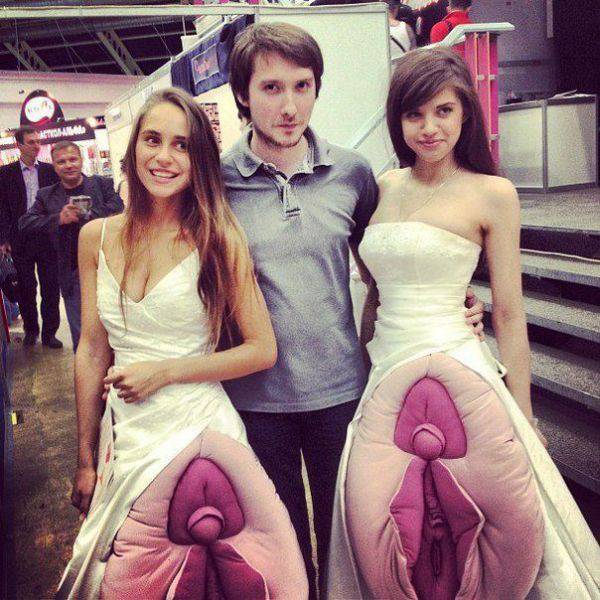 guy posing with two girls wearing massive vagina pillows over their prom dresses.