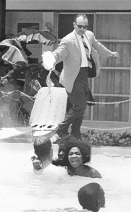 A hotel manager throwing acid into a pool while a black family are swimming