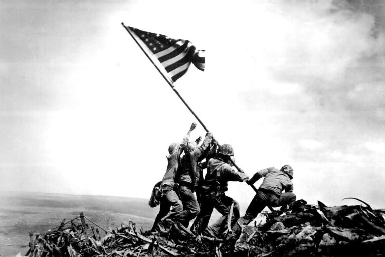 Raising the Flag on Iwo Jima - On February 23, 1945, Joe Rosenthal shot this photo of five Marines and one Navy corpsman raising a U.S. flag on Mt. Suribachi, on the fifth day of a battle that claimed the lives of 6,800 Americans and 21,000 Japanese. A smaller flag was initially raised, but a commander called for a larger, more easily-visible replacement to both inspire his men and demoralise his opponents. Rosenthal’s photo shows this second raising, which became a patriotic symbol of unity and won Rosenthal a Pulitzer Prize.