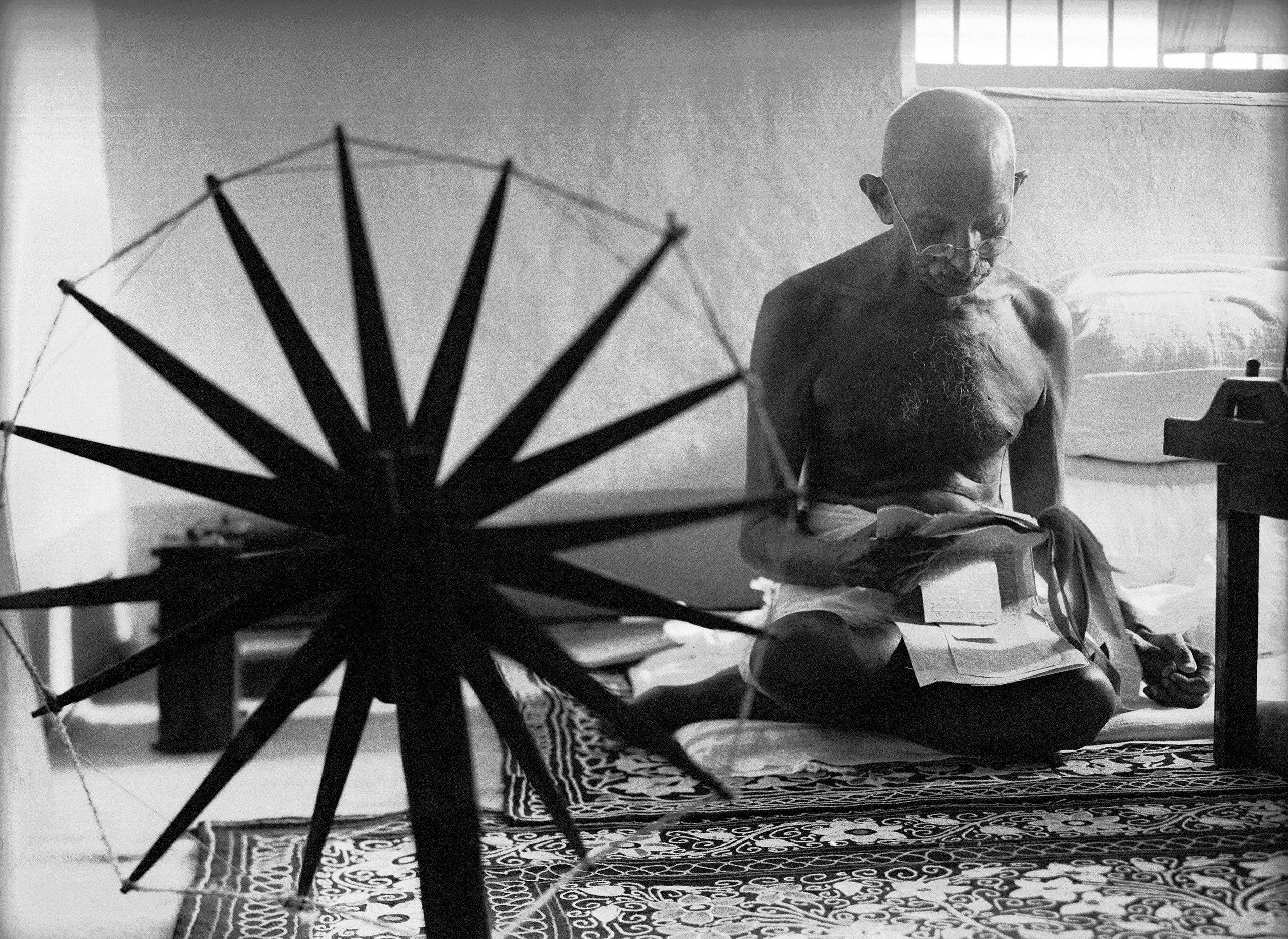 Gandhi and His Spinning Wheel - Perhaps the definitive photo of Mohandas Gandhi was taken by Margaret Bourke-White, LIFE magazine’s first female photographer. It depicts Gandhi reading the news next to his portable spinning wheel, which had become a potent exemplar of the campaign for independence after Ghandi had encouraged his countrymen to make their own homespun cloth instead of purchasing British goods.