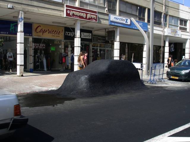 Weird picture of a car that's been paved over on the street