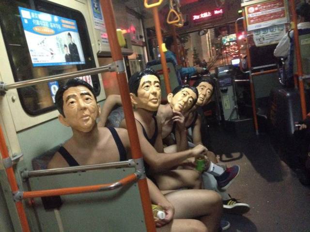 Weird picture of three guys all wearing the mask of an old asian guy on the subway