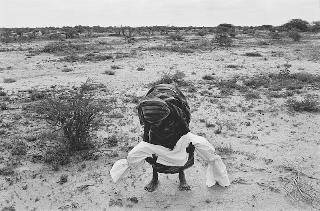 A mother carries her dead child to the grave, after wrapping it in a shroud according to local custom. A bad drought coupled with the effects of civil war caused a terrible famine in Somalia which claimed the lives of between one and two million people over a period of two years, more than 200 a day in the worst affected areas. The international airlift of relief supplies which started in July 1992 was hampered by heavily armed gangs of clansmen who looted food storage centers and slowed down the distribution of the supplies by aid organizations