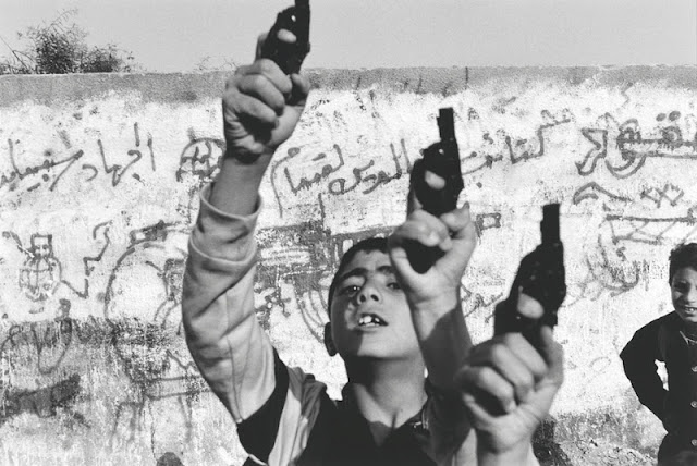 Boys raise toy guns in a gesture of defiance. The Palestinian uprising, which began in December 1987, strengthened the Arab population in their determination to fight the occupying force. In March Israel closed its border with Gaza, causing a massive rise in unemployment. With more than 800,000 people contained in the Israeli-patrolled, eight-km-wide strip of land, bloodshed increased sharply. The peace agreement signed in Washington on September 13,1993 promised limited authority for the Gaza Strip and a withdrawal of the Israeli army