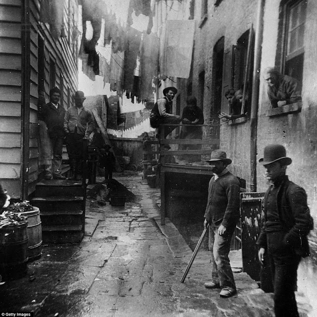 In an astonishingly atmospheric image taken in 1887, a group of men loiter in an alley known as 'Bandit's Roost' off Mulberry Street