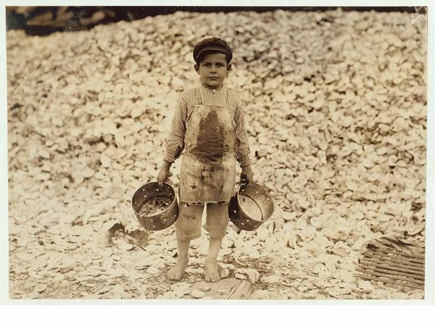 Manuel and a mountain of child-labor oyster shells behind him. He worked last year. Understands not a word of English. Dunbar, Lopez, Dukate Company. Location: Biloxi, Mississippi.