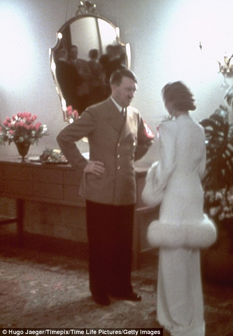Hitler chats to a glamorously dressed woman as they Nazis enjoy a party