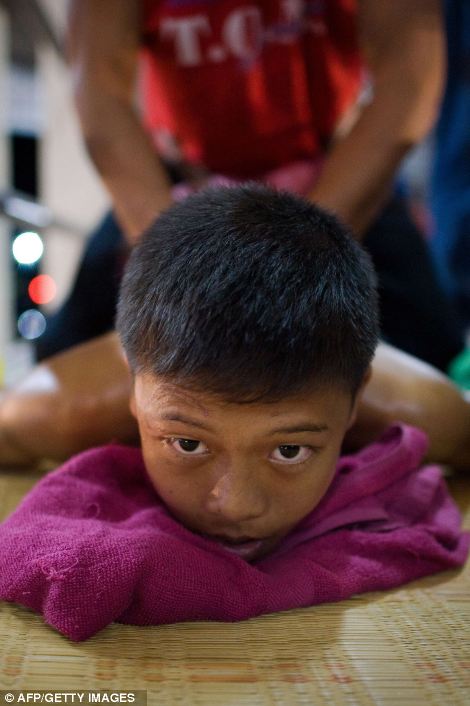 getting a massage from his coach ahead of his fight at a boxing stadium in Buriram province