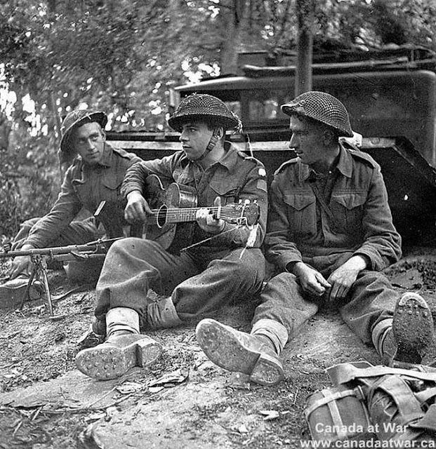 Canadian Soldiers rest during the Battle of Caen and play the guitar. June-August 1944