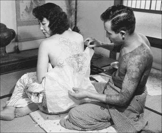A Japanese artist tattoos a pattern to a customers back, 1955