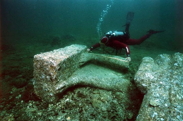 An archaeologist measures the feet of a colossal red granite statue at the site of Heracleion discovered in Aboukir Bay.