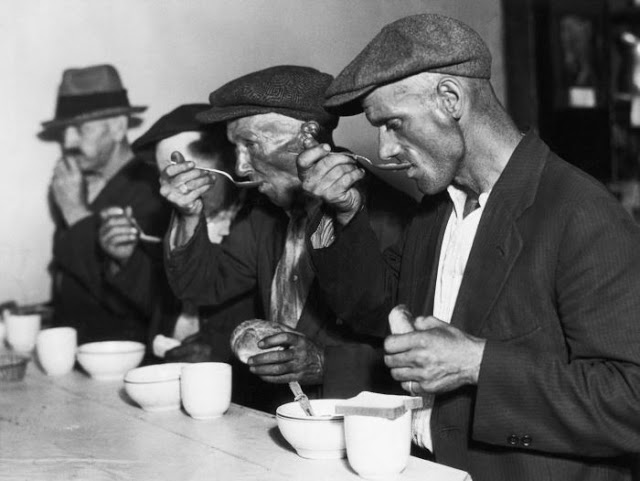 Men eating bread and soup in a breadline during the Great Depression