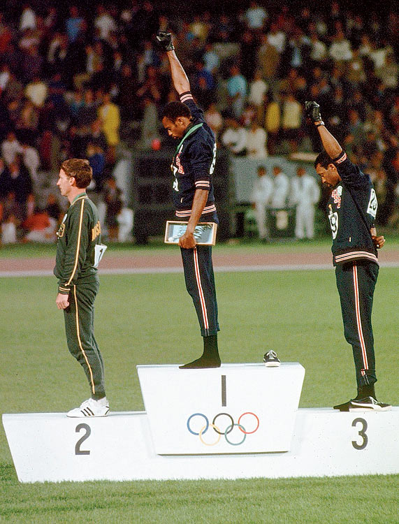 American sprinters Tommie Smith center and John Carlos right raise their black-gloved fists on the Olympic medal podium in Mexico City to signify Black Power. Smith, the gold medalist in the 200-meter race, and Carlos, the bronze medalist, were kicked out of the Games for their overtly political statement