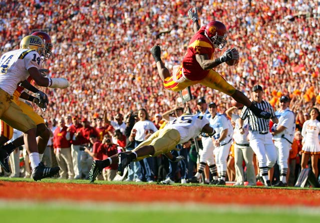 USC running back Reggie Bush jump over UCLA defender Marcus Cassel and into the end zone for a touchdown. Bushs spectacular season earned him the 2005 Heisman Trophy, but the award was later stripped because Bush had received illegal benefits during his time with the Trojans.
