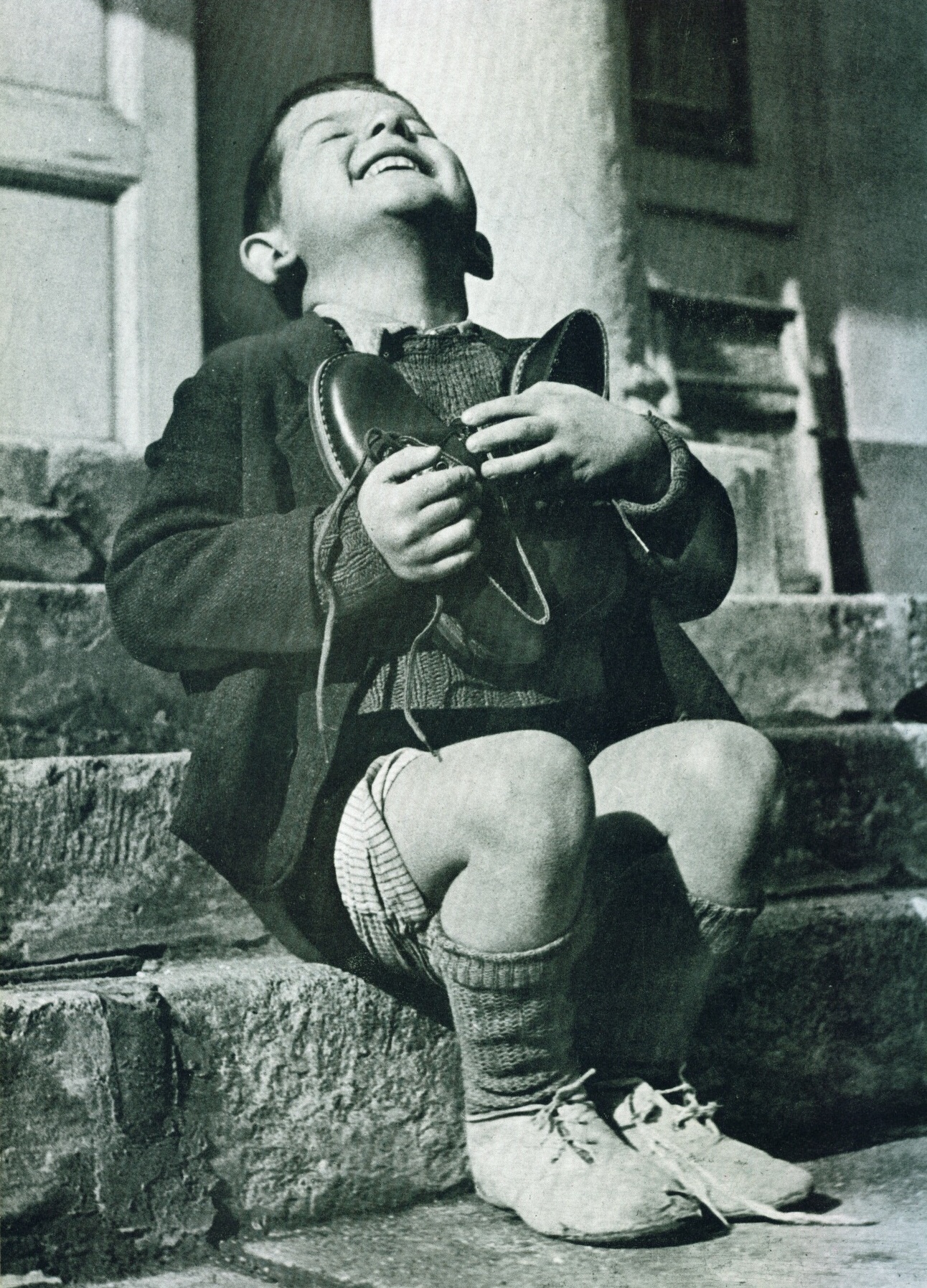 A 6 year-old boy, living in an orphanage in Austria rejoices and hugs a new pair of shoes given to him by the American Red Cross. 1946