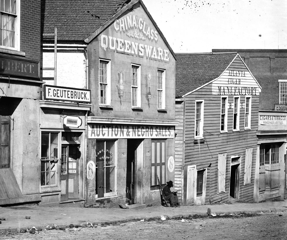 A black Union soldier sits, posted in front of a slave auction house on Whitehall Street in Atlanta, Georgia, in 1864