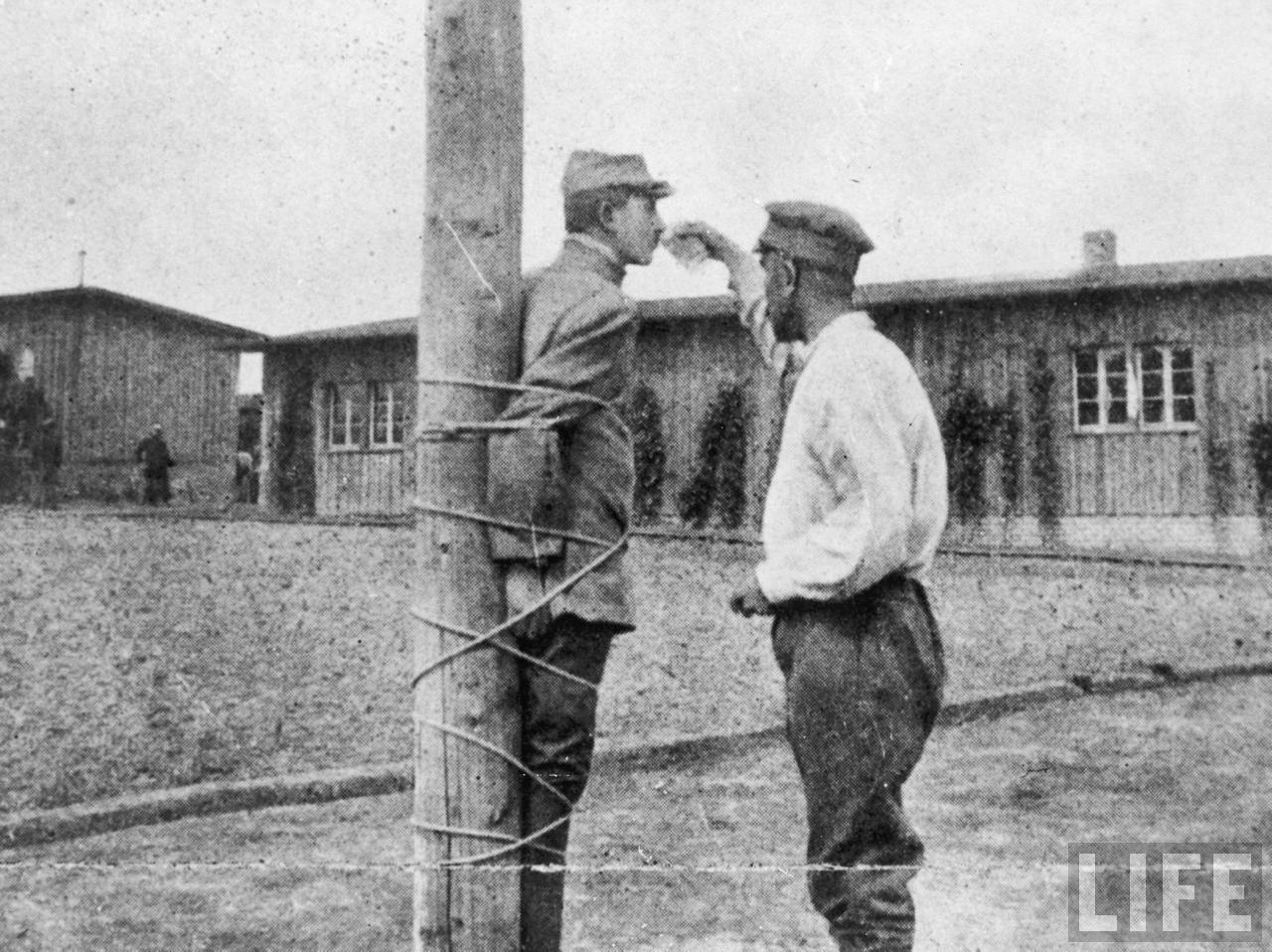 French prisoner tied to a stake at Zwickau prison camp is given a drink by a fellow POW, Germany, 1917