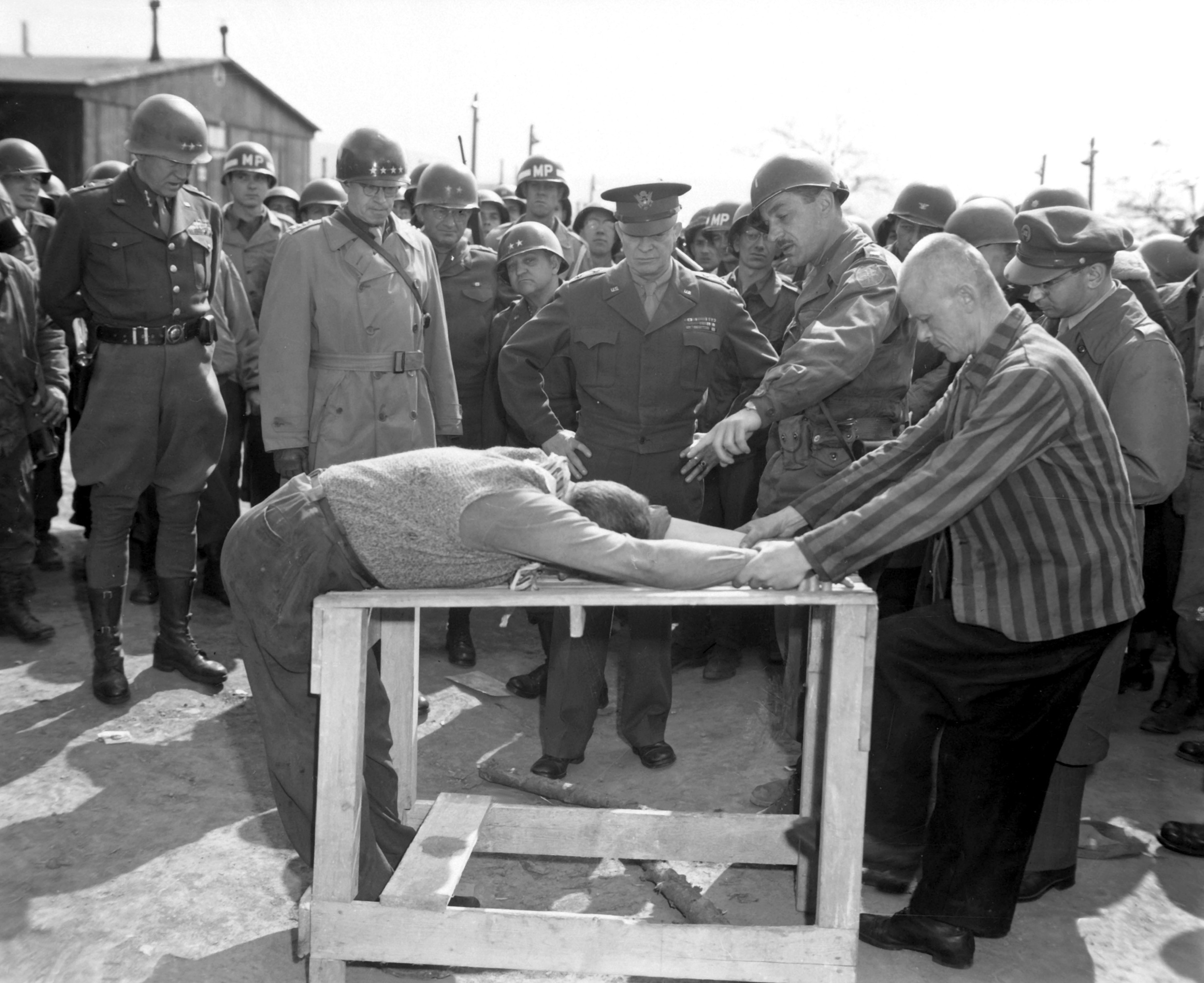 General Eisenhower watches occupants of Ohrdruf concentration camp demonstrate how they were tortured, Generals Bradley and Patton are at his right, April 12 1945