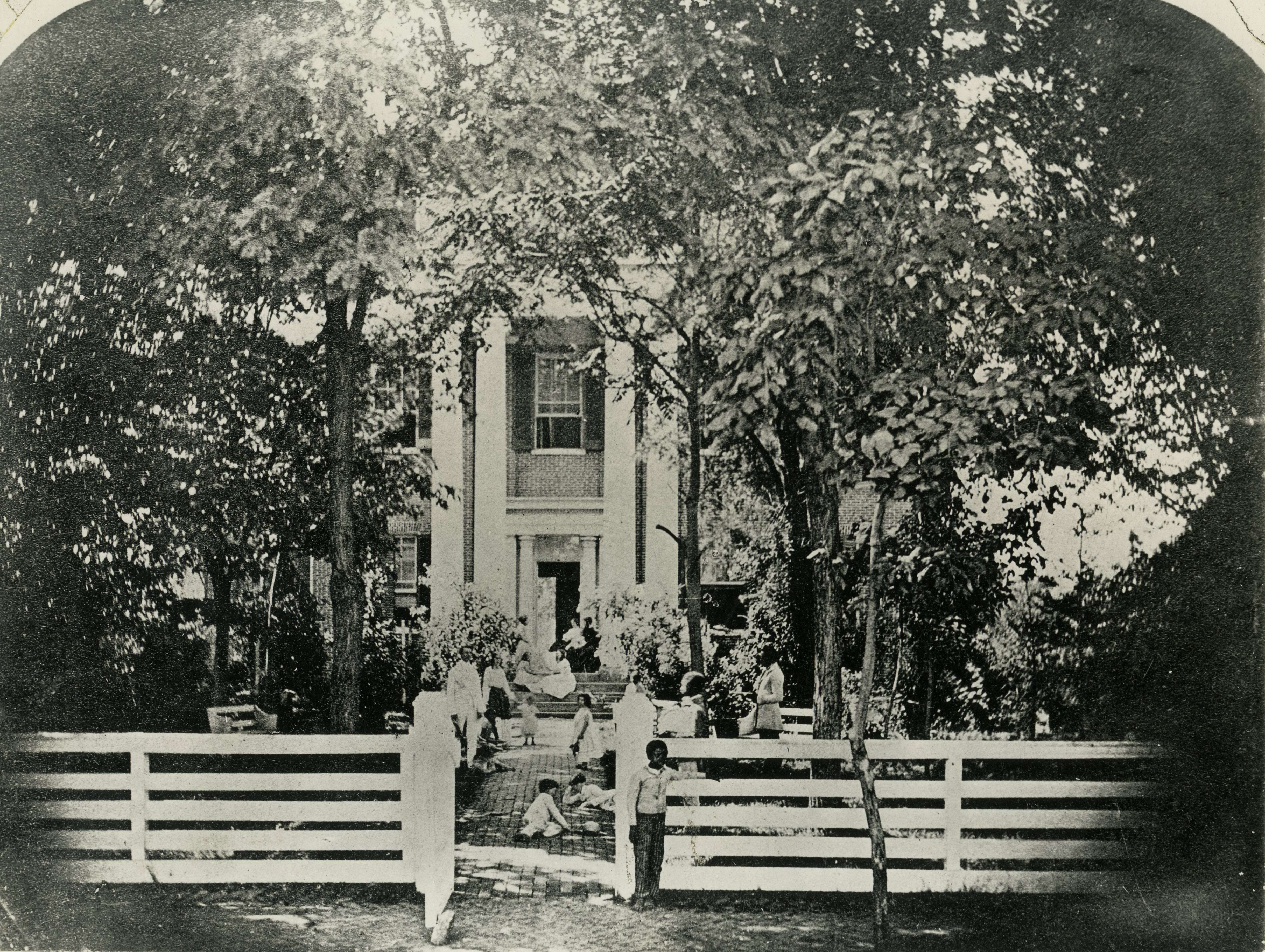 A slave-owning family posing in the front yard of their house with at least three of their slaves visible, Kentucky, c. 1850s