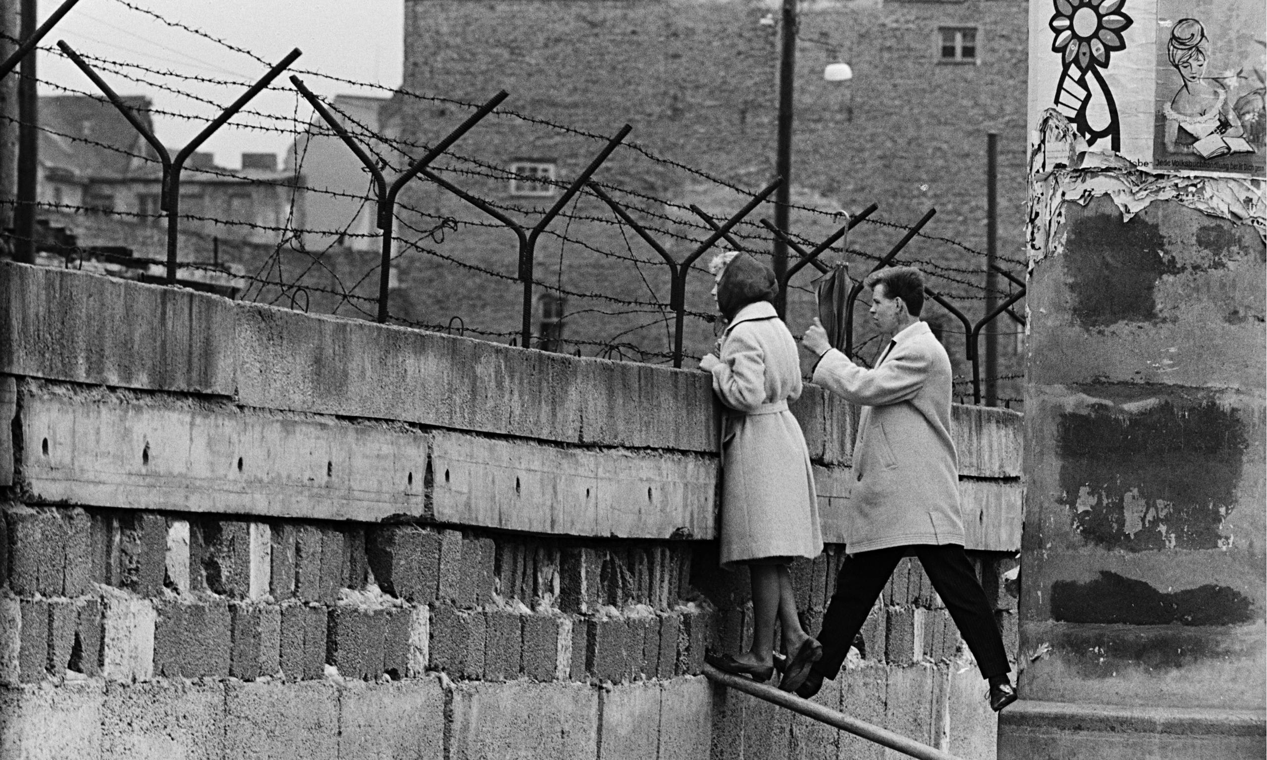 A young West Berlin couple peer over the Wall as the woman speaks to her mother in East Berlin, 1960s
