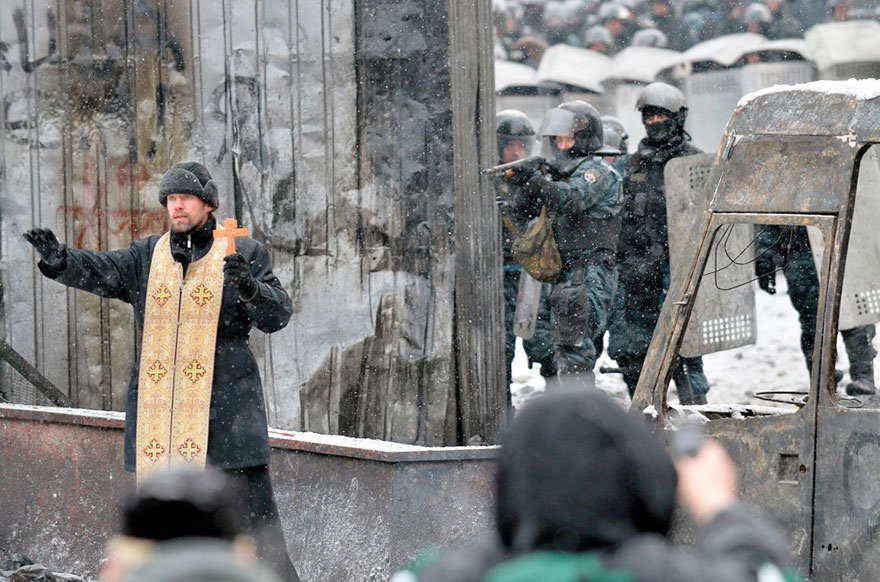 Orthodox priest attempting to prevent a clash between protestors and police in Kiev, Ukraine, 2014.
