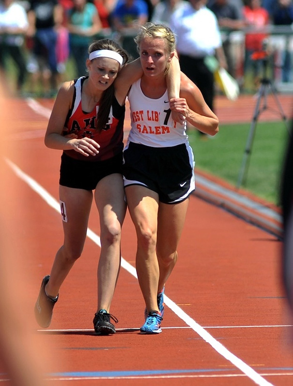 Ohio track athlete helping an injured competitor across the finish line at a state meet.
