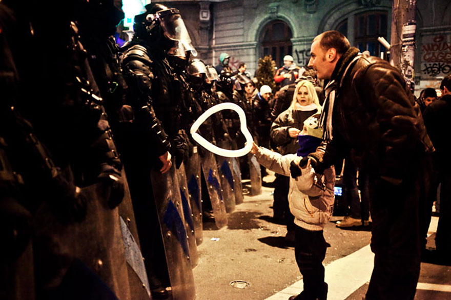 Young boy giving a heart-shaped balloon to riot police in Bucharest, Romania, 2012.