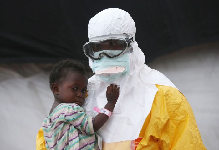 A Doctors Without Borders MSF worker in protective clothing holds a child suspected of having Ebola at a treatment center in Paynesville, Liberia, on Oct. 5.