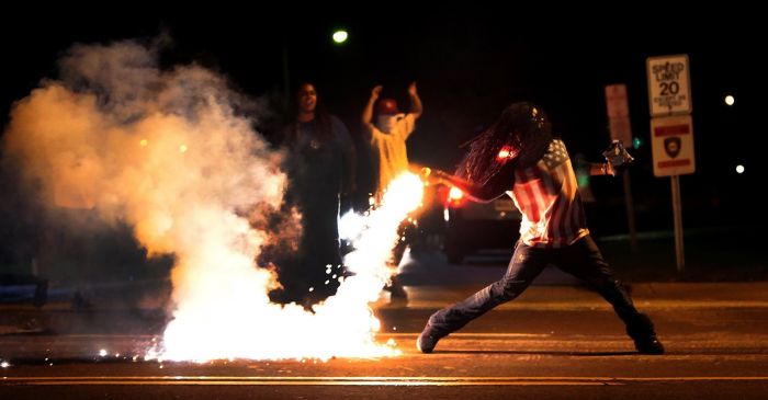 A demonstrator throws a tear gas container back at police officers in Ferguson, Missouri, on Aug. 13