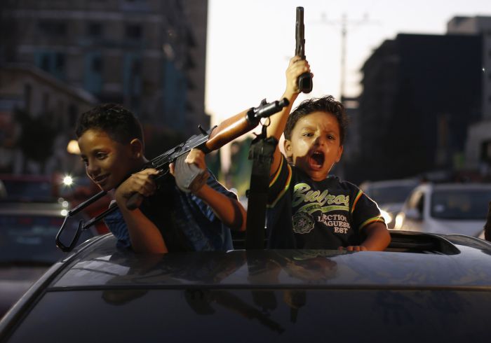 Palestinian children hold guns as they celebrate with others what they said was a victory over Israel, following a ceasefire in Gaza City, Aug. 26