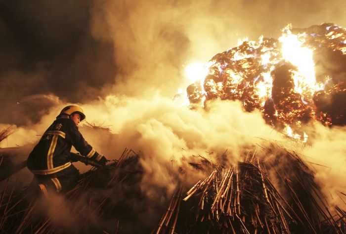 A firefighter attempts to extinguish a fire that broke out on piles of reeds at a paper factory in Changde, Hunan province, Feb. 16