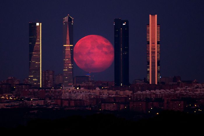 The moon shines through the Four Towers Madrid skyscrapers on Aug. 11, in Madrid, Spain.