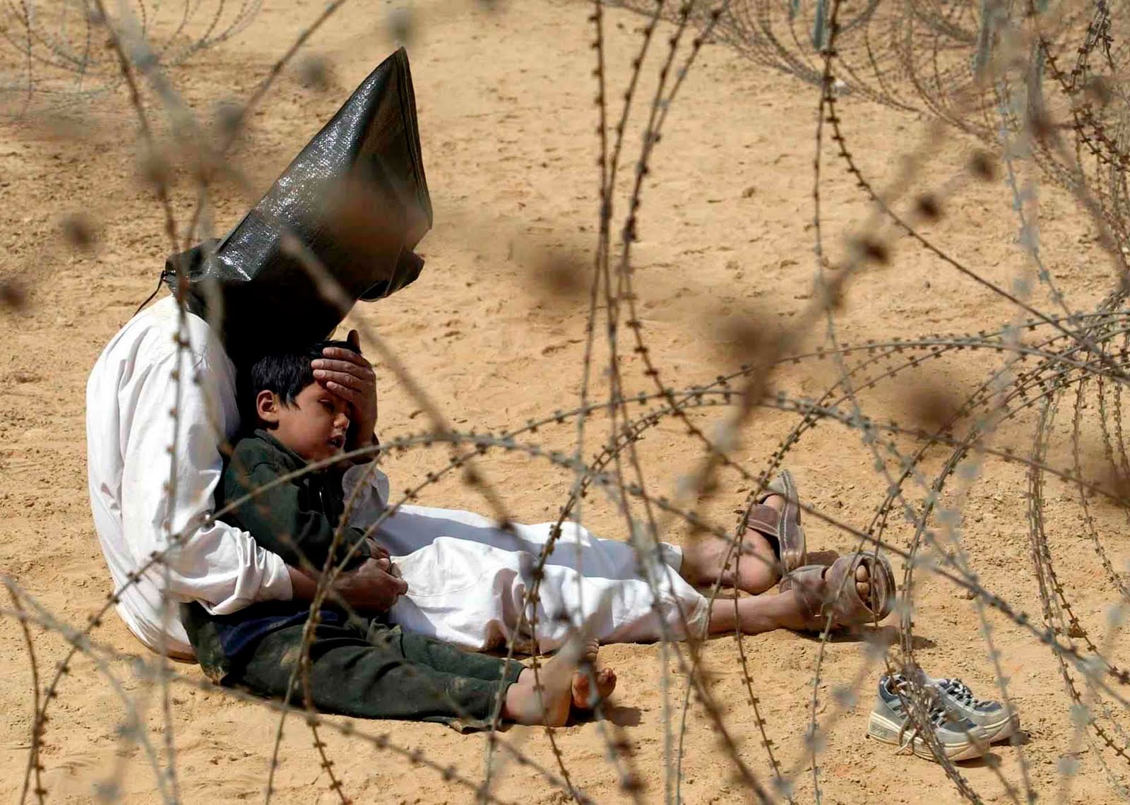 An Iraqi man comforts his son at a holding center for prisoners of war in An Najaf, Iraq, 31 March 2003.