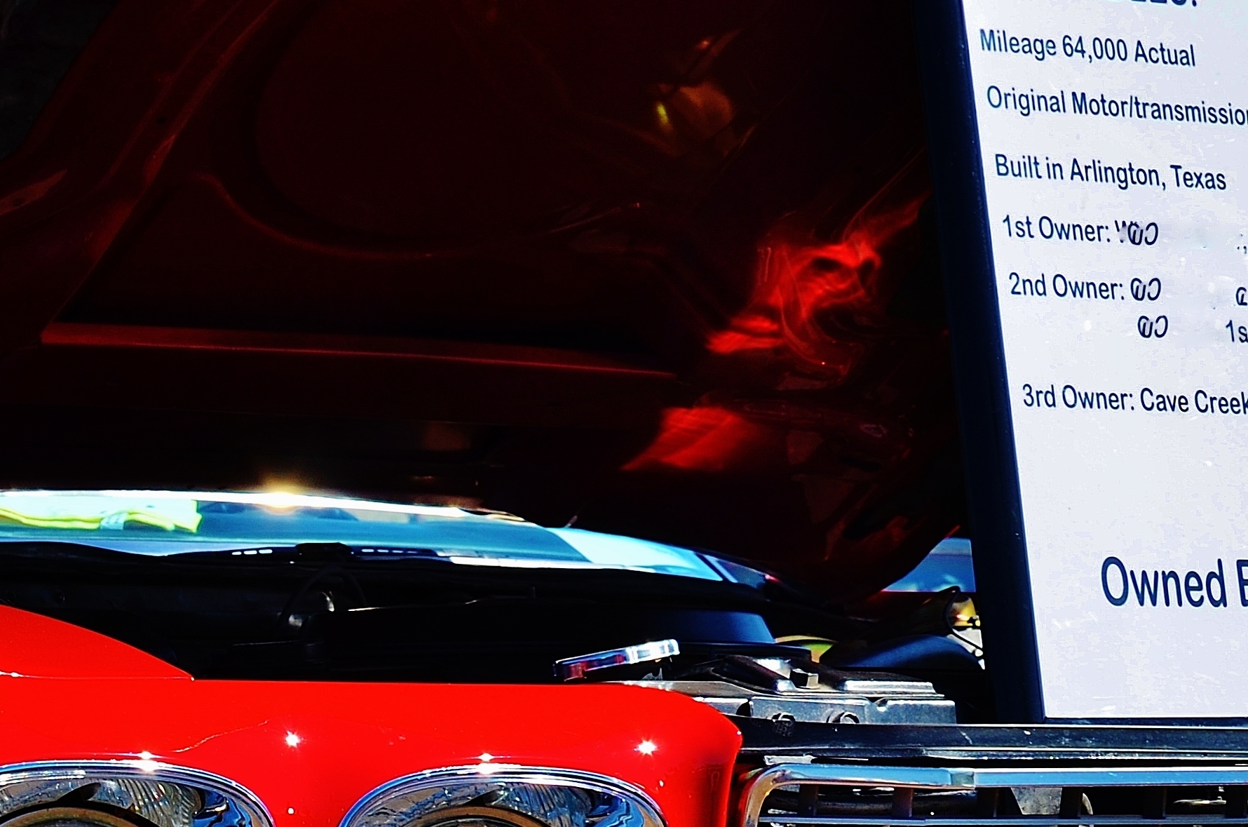 The reflection of a demon under the hood of a 1970 Chevelle at a car show