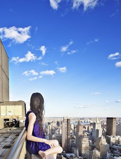 Ahn sits on the edge of a rooftop overlooking New York City