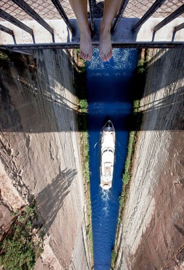 The artist dangles her feet over a bridge in Greece.