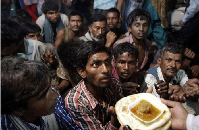 Indian homeless men wait to receive free food distributed outside a mosque ahead of Eid al-Fitr in New Delhi, India