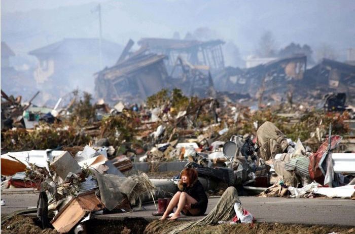 A woman sits amidst the wreckage caused by a massive earthquake and ensuing tsunam, in Natori, northern Japan, in March 2011