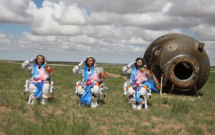 Chinese astronauts L-R Zhang Xiaoguang, Nie Haisheng and Wang Yaping salute after getting out of the re-entry capsule of China's Shenzhou X spacecraft following its successful landing at the main landing site in Inner Mongolia Autonomous Region of China.