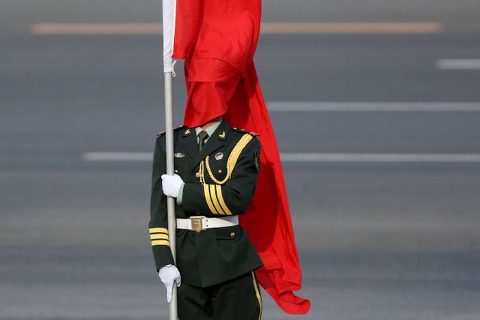 The wind blows a red flag onto the face of an honour guard before a welcome ceremony for Australia's Prime Minister Julia Gillard outside the Great Hall of the People in Beijing, China. At the invitation of Chinese Premier Li Keqiang, Australian Prime Minister Julia Gillard will pay an official visit to China after the Boao Forum for Asia Annual Conference 2013