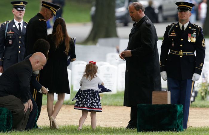 Four-year-old Sophia Phillips carries an American flag presented to her during a burial service for her father, Staff Sergeant Francis G. Phillips, at Arlington National Cemetery in Arlington Virginia. Phillips, from Meridian, New York was killed in combat in the Maiwand district of Afghanistan when the vehicle he was riding in was struck by an improvised explosive device.