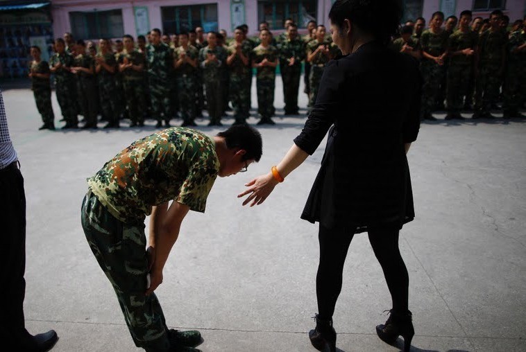 A student who completed a six-month course bows to the head teacher.